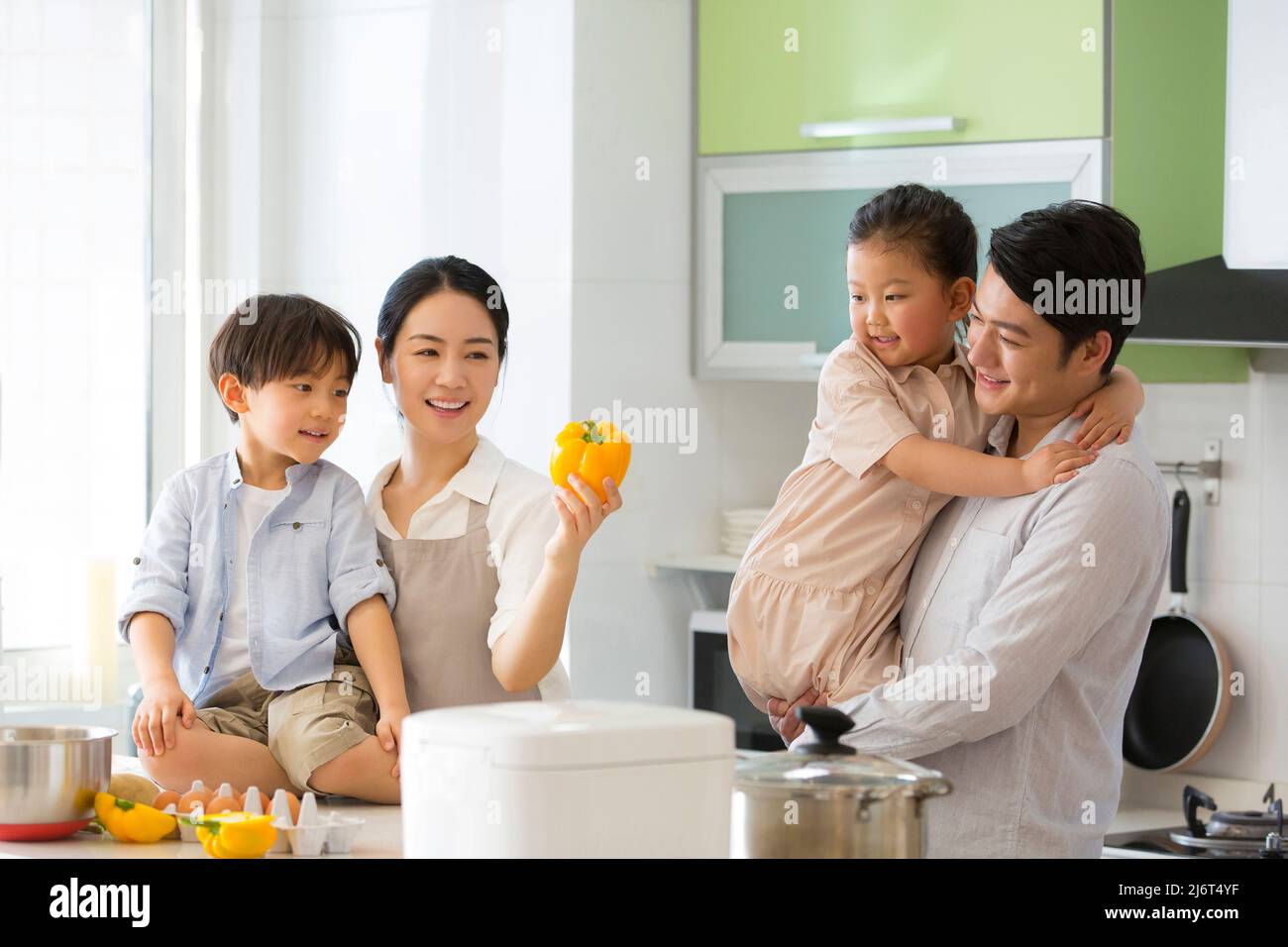 Famiglia parentage. Un giovane genitore gioca con due preschoolers mentre la madre insegna loro una fiaba circa i peperoni dolci. - foto di scorta Foto Stock