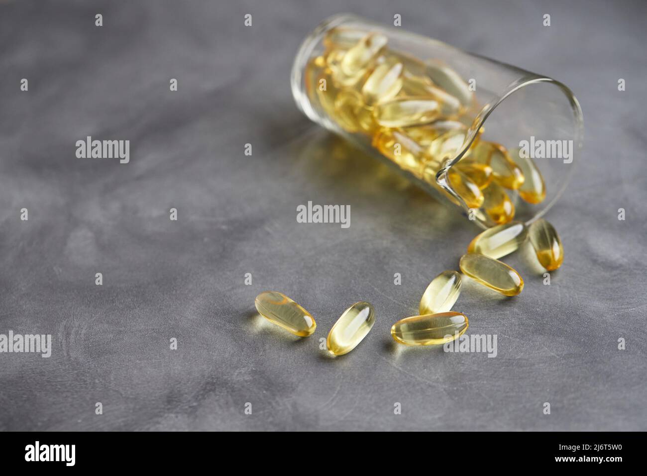 Capsule di acidi grassi omega-3 su sfondo grigio. Il concetto di medicina e uno stile di vita sano. Vista frontale. Foto Stock