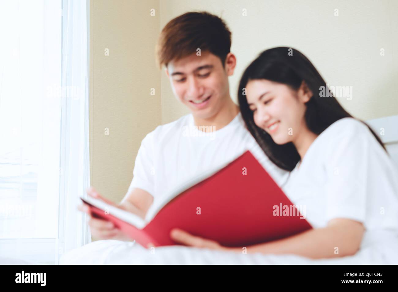 coppie asiatiche che progettano per i libri di sguardo di futuro, assicurazione di vita di acquisto, case di acquisto, guardando le foto di nozze. Foto Stock