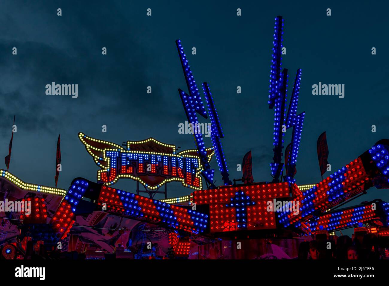 Le luci blu e rosse del funfair Jetfire illuminano il cielo notturno. Foto Stock