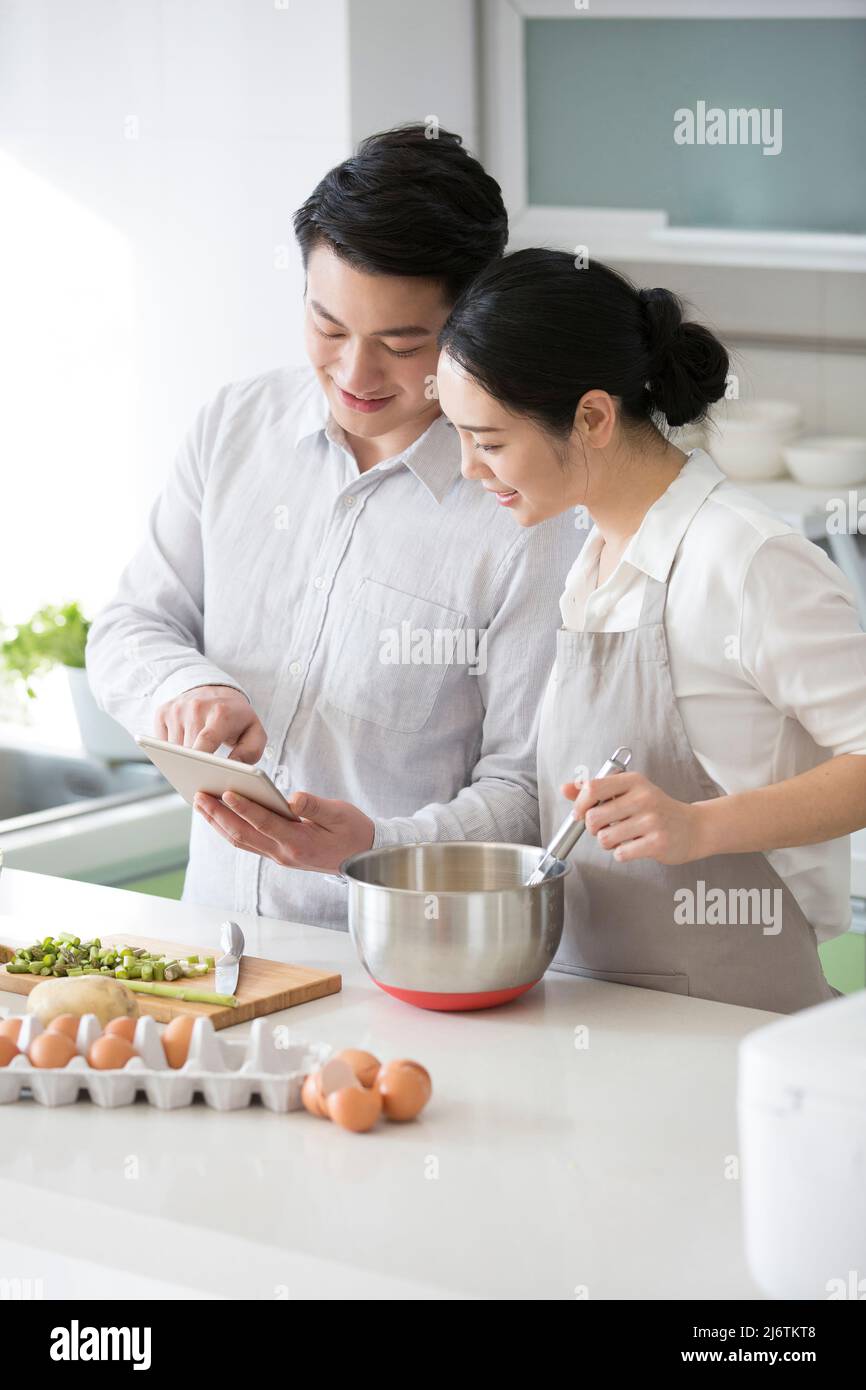 Nella cucina di famiglia, una giovane coppia piace cucinare insieme e utilizzare i tablet per controllare gli acquisti futuri - foto di scorta Foto Stock