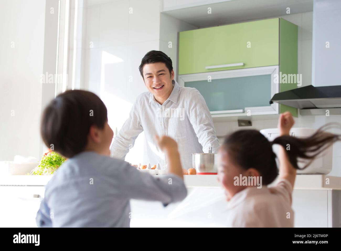 Famiglia cucina parentage. Gli occhi del giovane padre sono pieni di gioia mentre guarda due bambini che giocano da soli. - foto di scorta Foto Stock