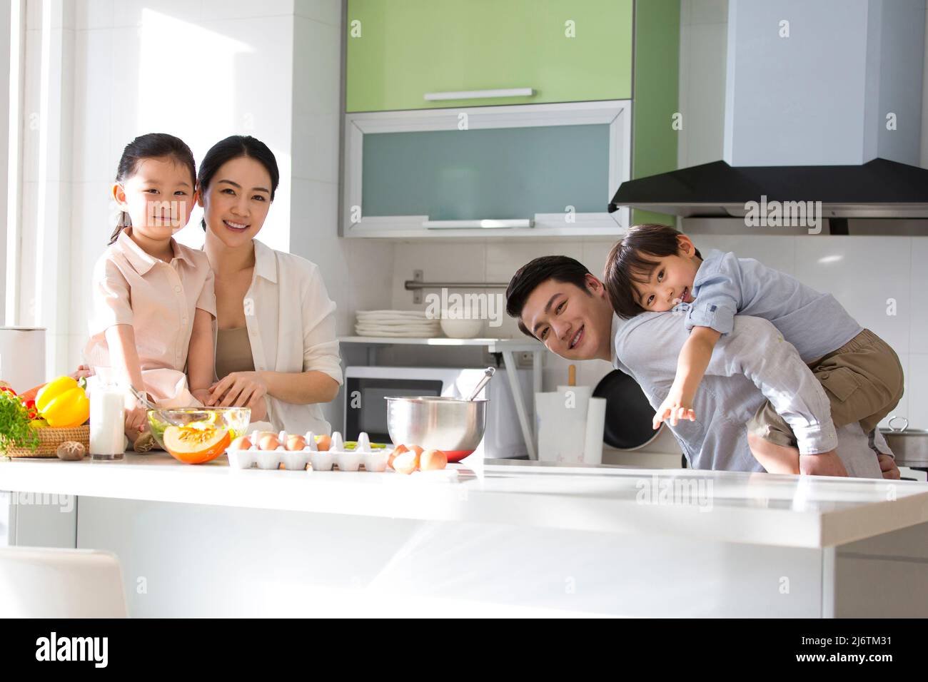 Famiglia parentage. Giovani genitori che giocano con i loro figli in cucina, padre che porta il figlio che gode felicemente la giornata. - foto di scorta Foto Stock