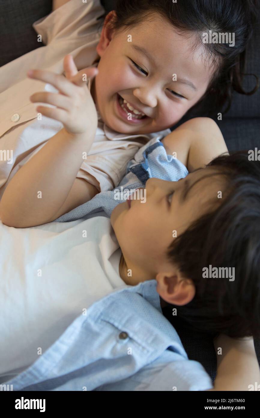 Una bambina e un ragazzino sdraiati sul divano chiacchierando felicemente - foto di scorta Foto Stock