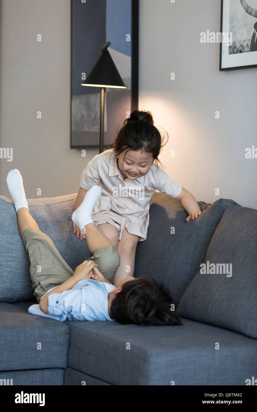 Una bambina e un ragazzino che giocano sul divano - foto d'archivio Foto Stock
