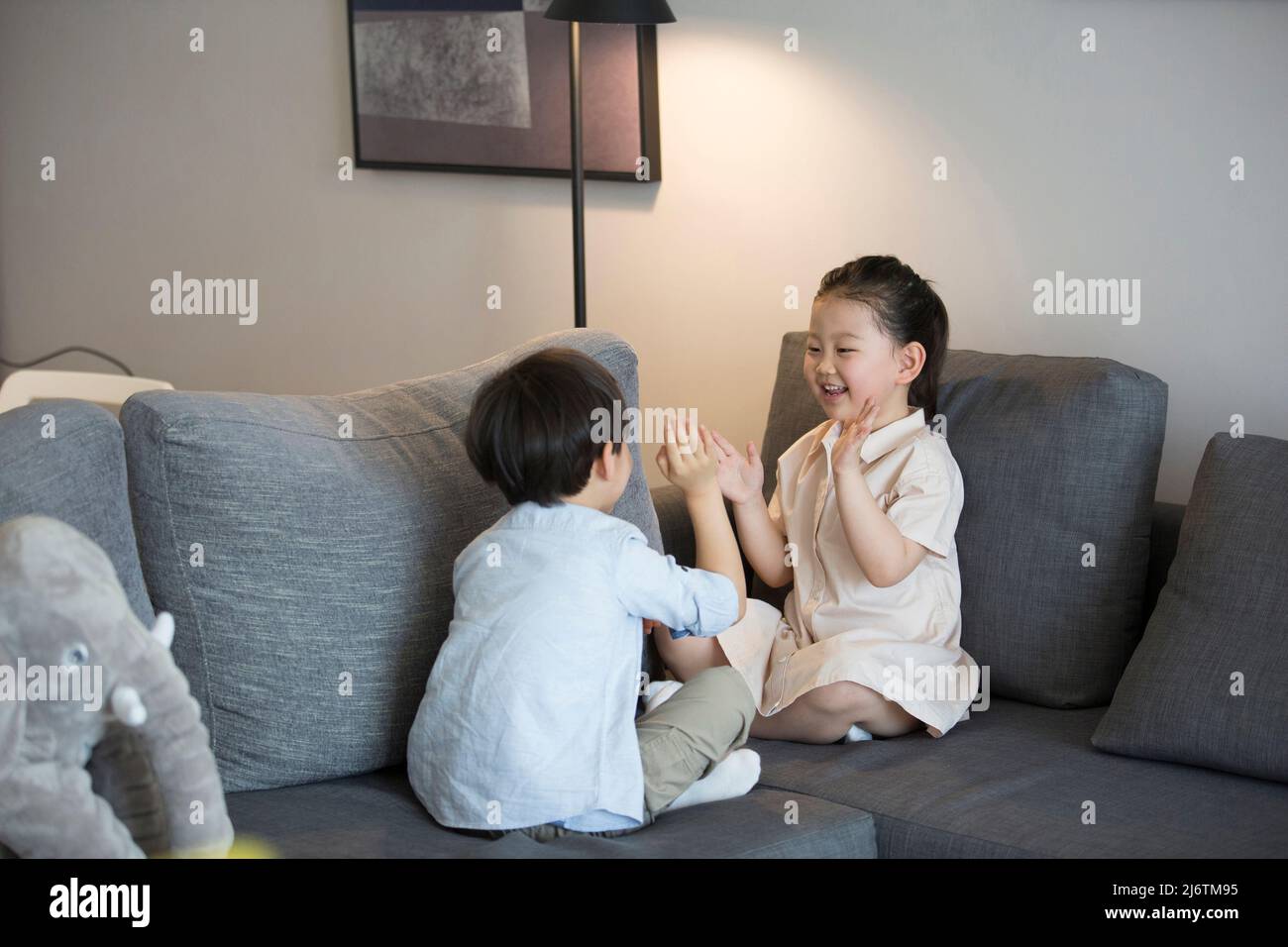 Una bambina e un ragazzino stanno giocando a fare un clic a mano sul divano del soggiorno - foto di scorta Foto Stock