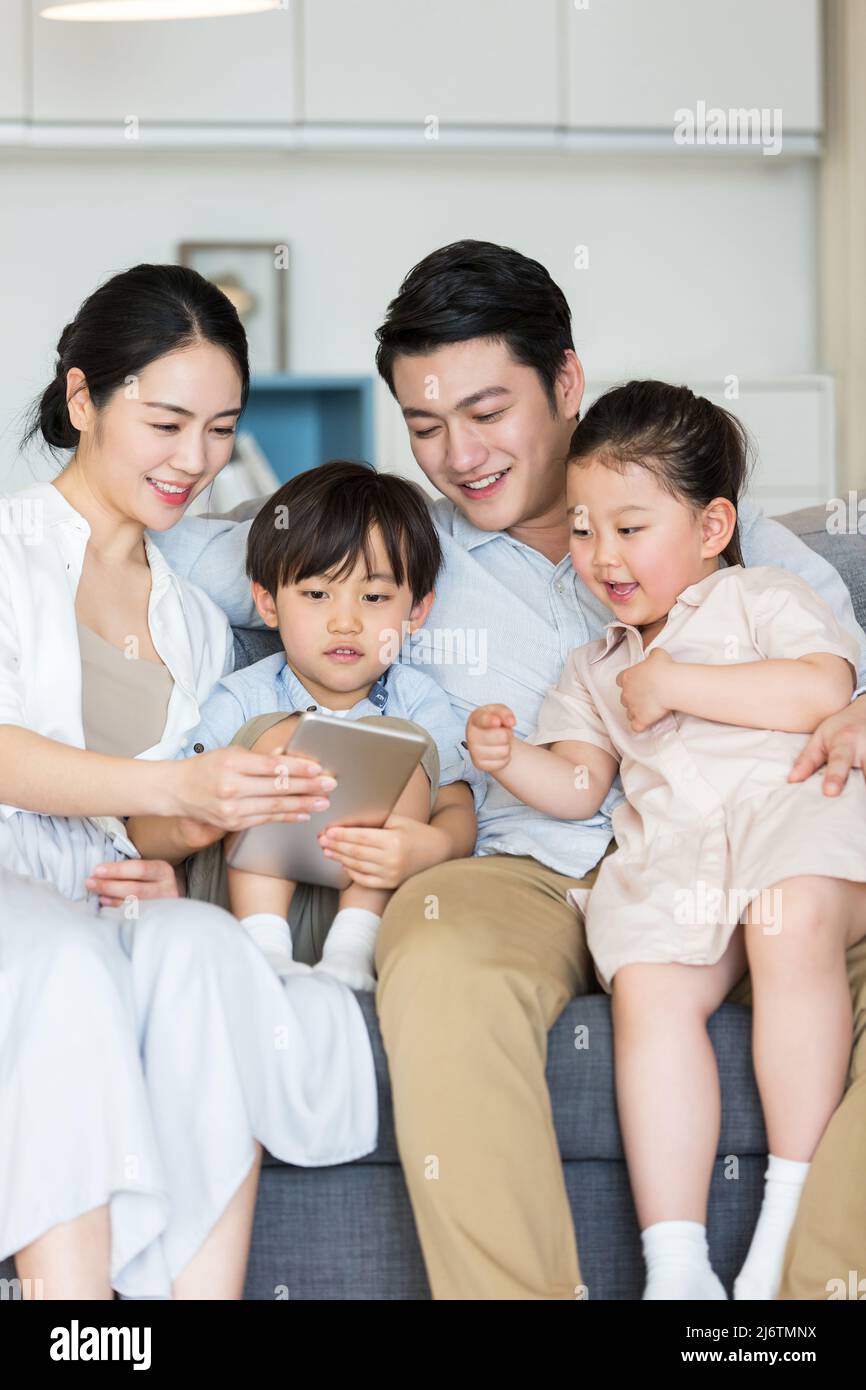 Coppia giovane che usa un tablet digitale con i loro due figli per imparare le lezioni di prescolare - foto di scorta Foto Stock