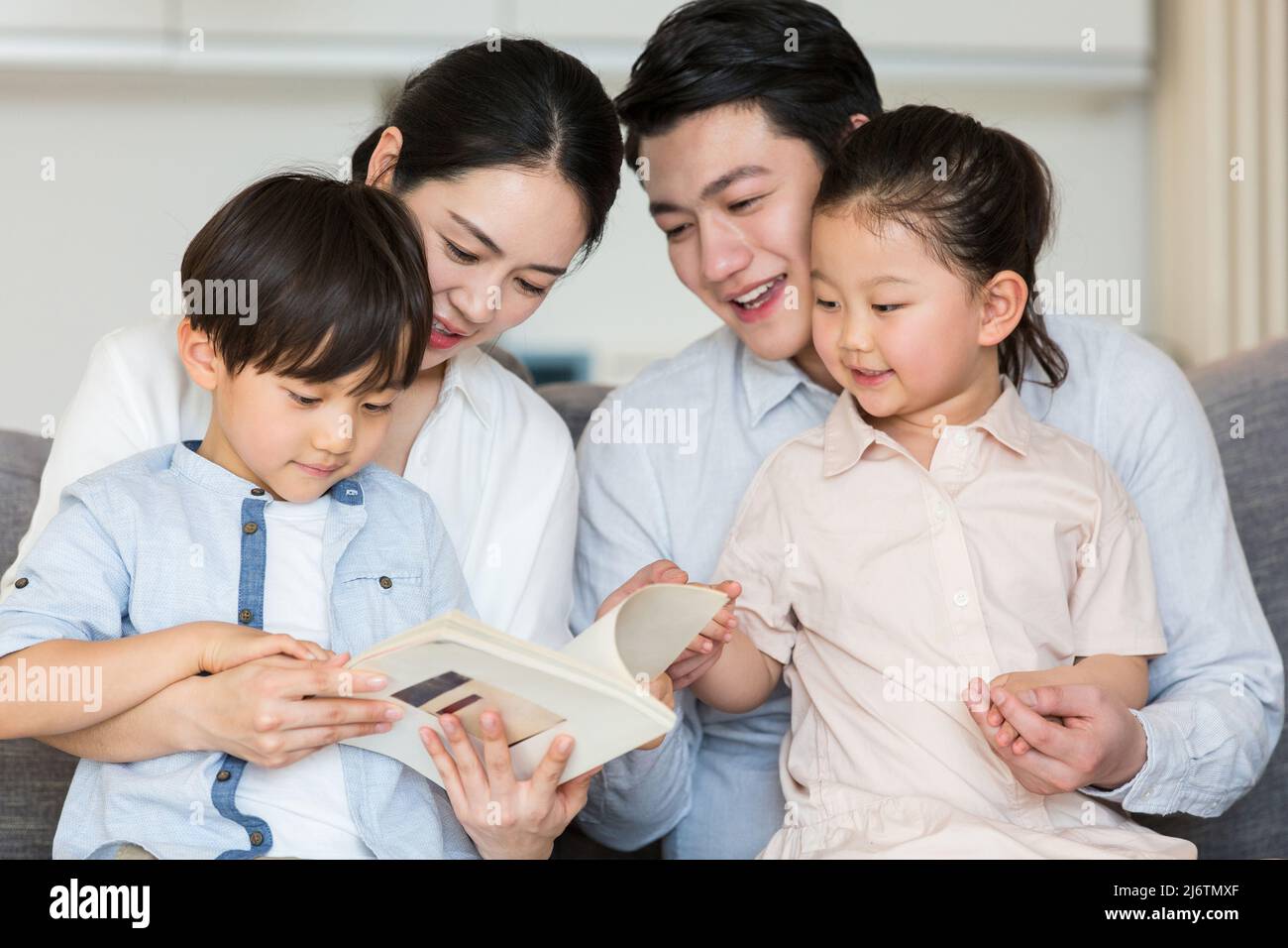 Un paio di genitori che leggono uno storybook per bambini con i loro due figli e figlie - foto di scorta Foto Stock