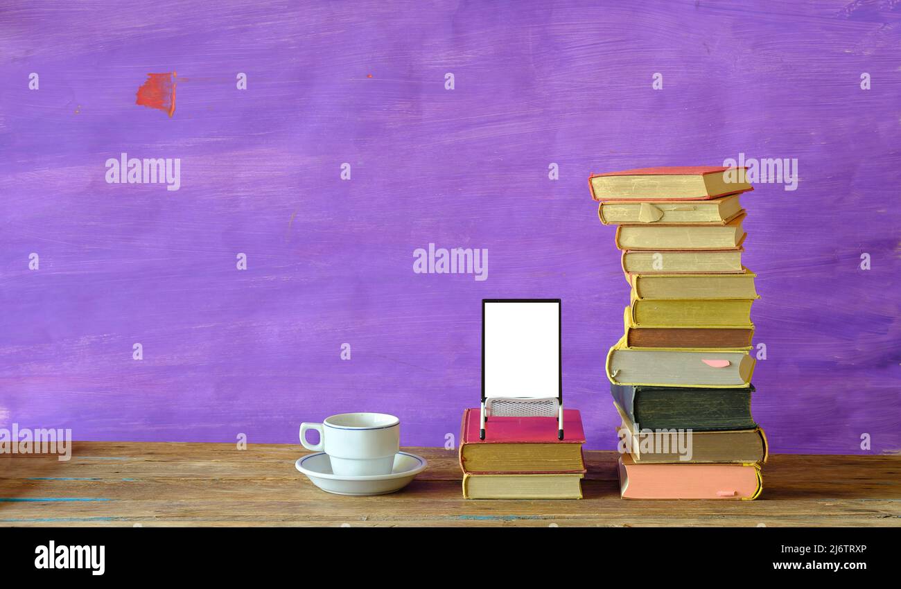 Concetto di e-book, con pila di libri, lettore di e-book con schermo blamk e una tazza di caffè, tecnica di spazio negativo, buona copia spazio Foto Stock