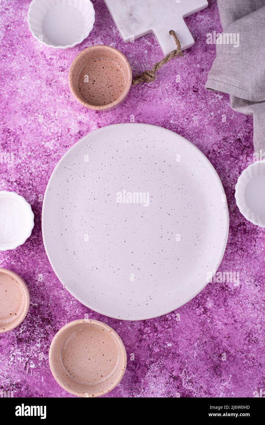 Piatto, ciotole e tagliere su fondo lilla Foto Stock
