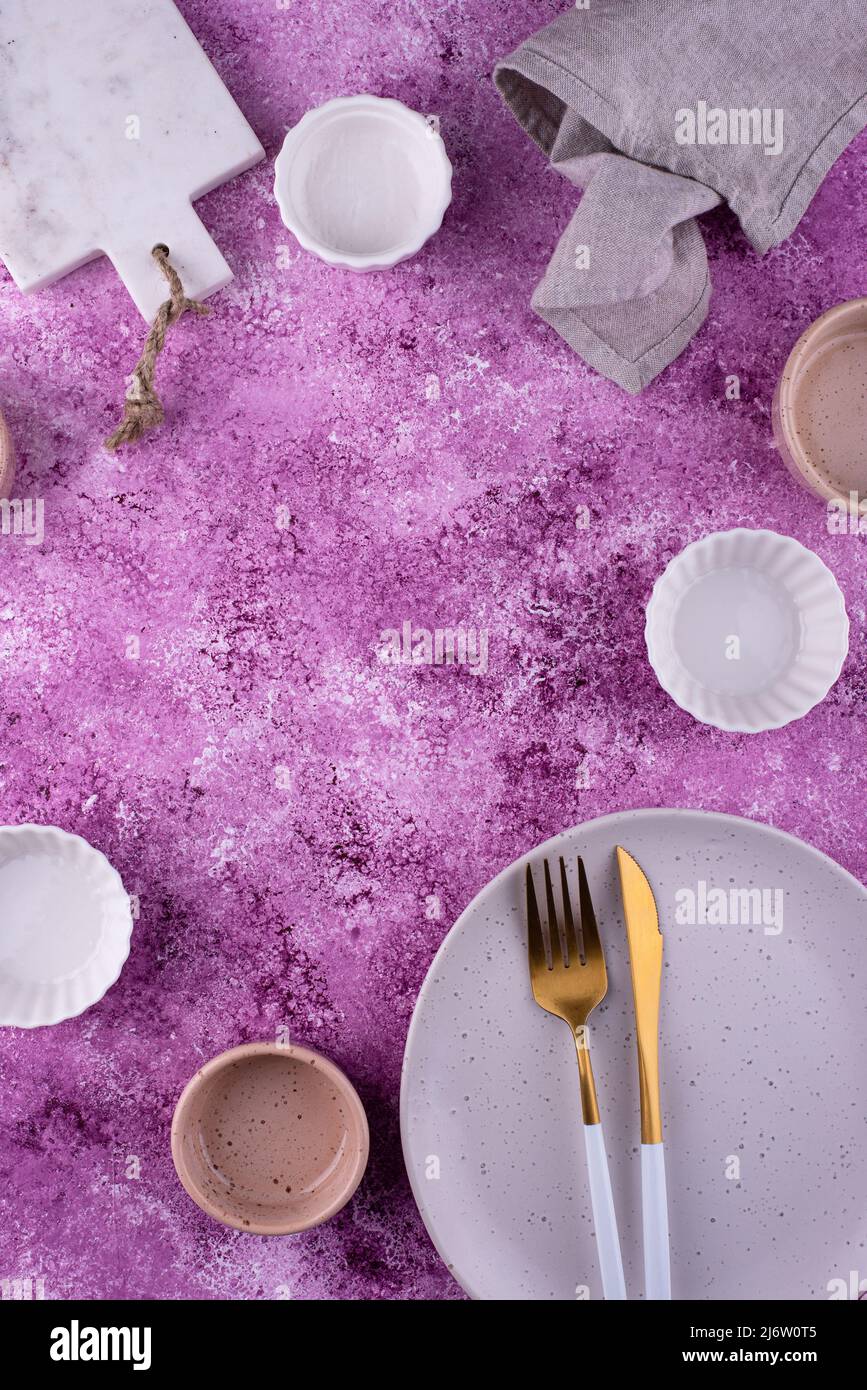 Piatto, ciotole e tagliere su fondo lilla Foto Stock