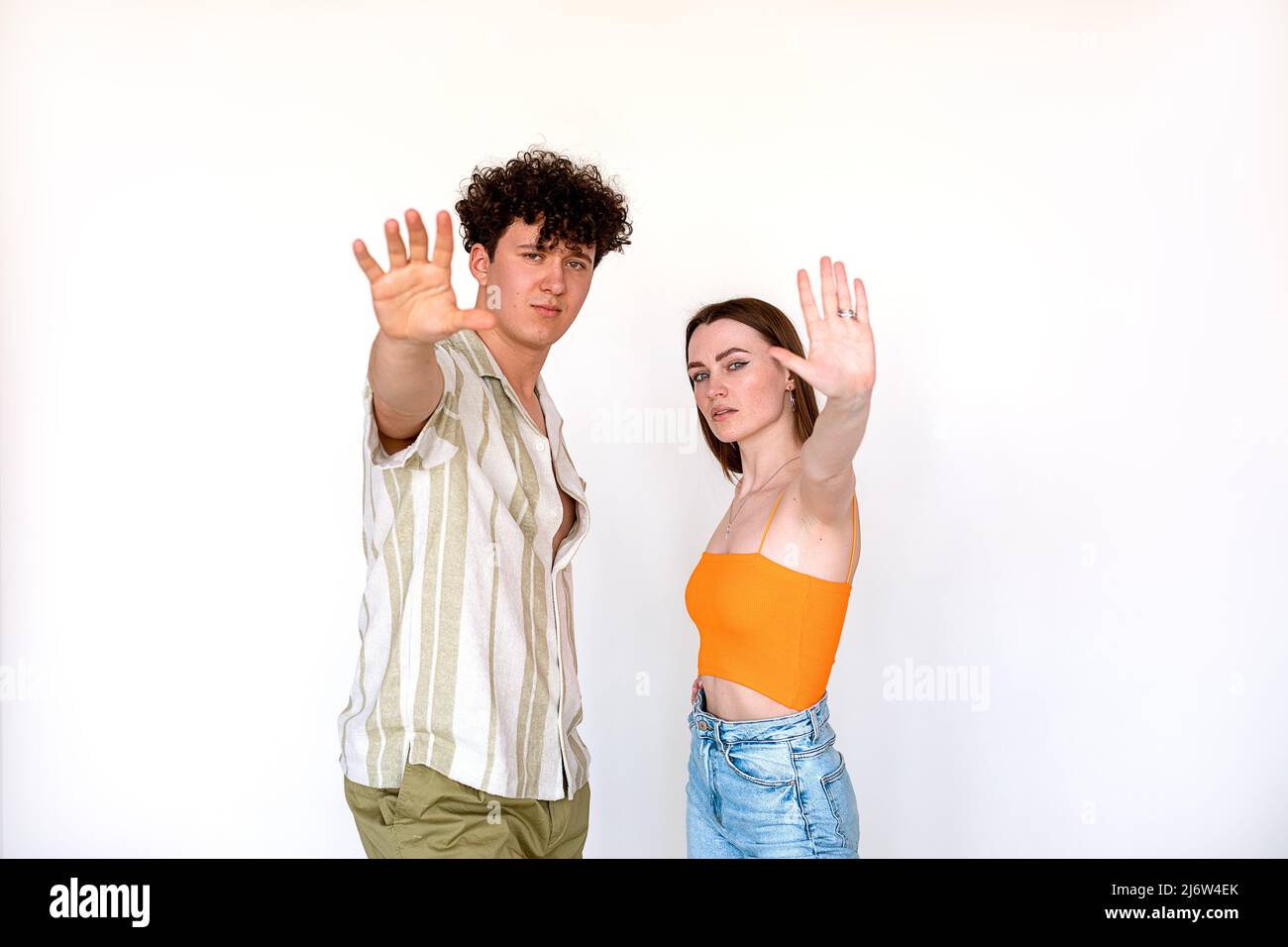 Ritratto di giovane coppia fiduciosa bella in posa su sfondo bianco. Giovane uomo, donna con palma aperta, cinque segni. Foto Stock