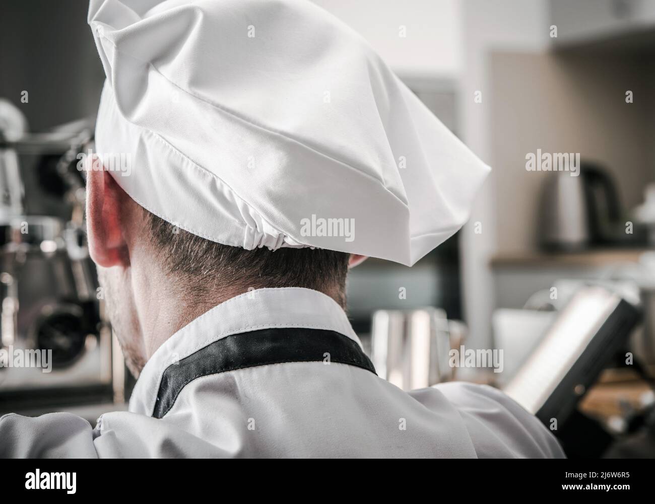 Cuoco della cucina caucasica che indossa un cappello Vista posteriore primo piano. Gastronomia industria tema. Foto Stock