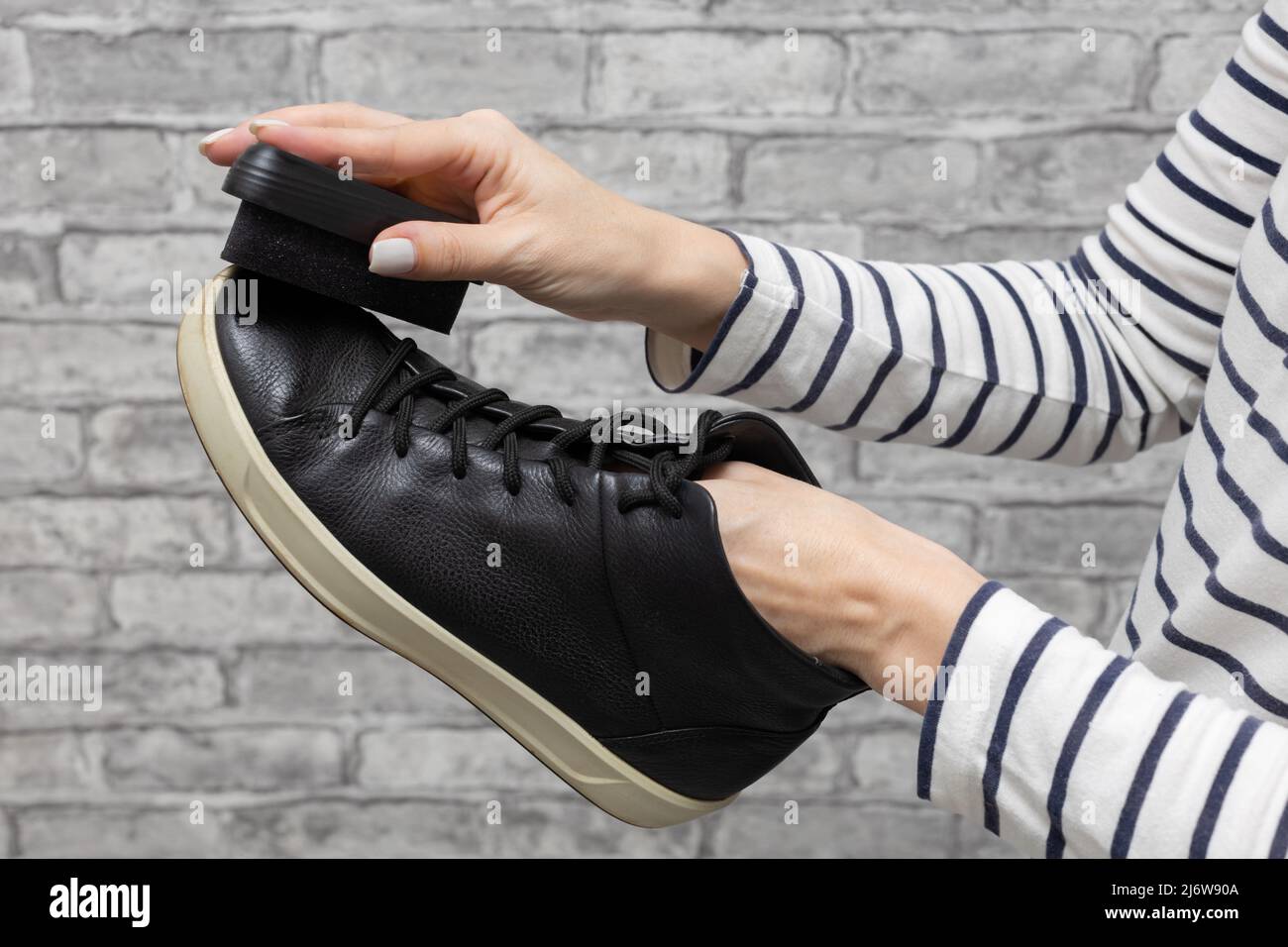donna strofinando le sue scarpe nere con una spugna. Foto di alta qualità Foto Stock