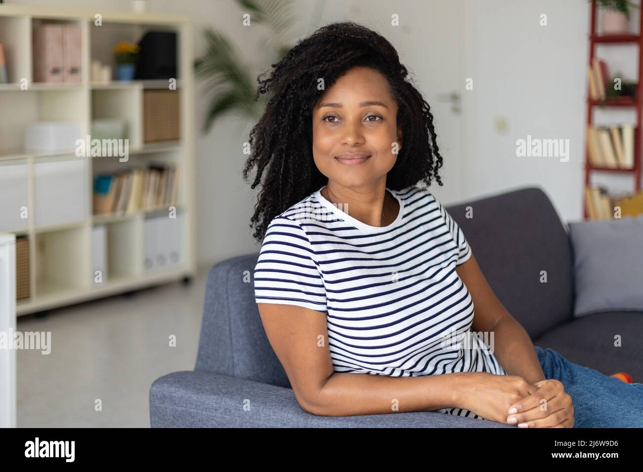 Giovane donna che si gode un piacevole momento di relax su un divano a casa. Foto Stock