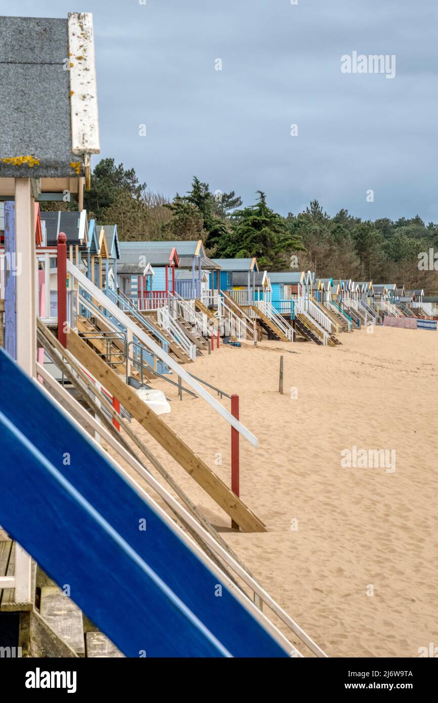 Capanne sulla spiaggia a Wells-next-the-Sea sulla costa nord del Norfolk, con scalini per le entrate innalzate sopra il livello della spiaggia. Foto Stock