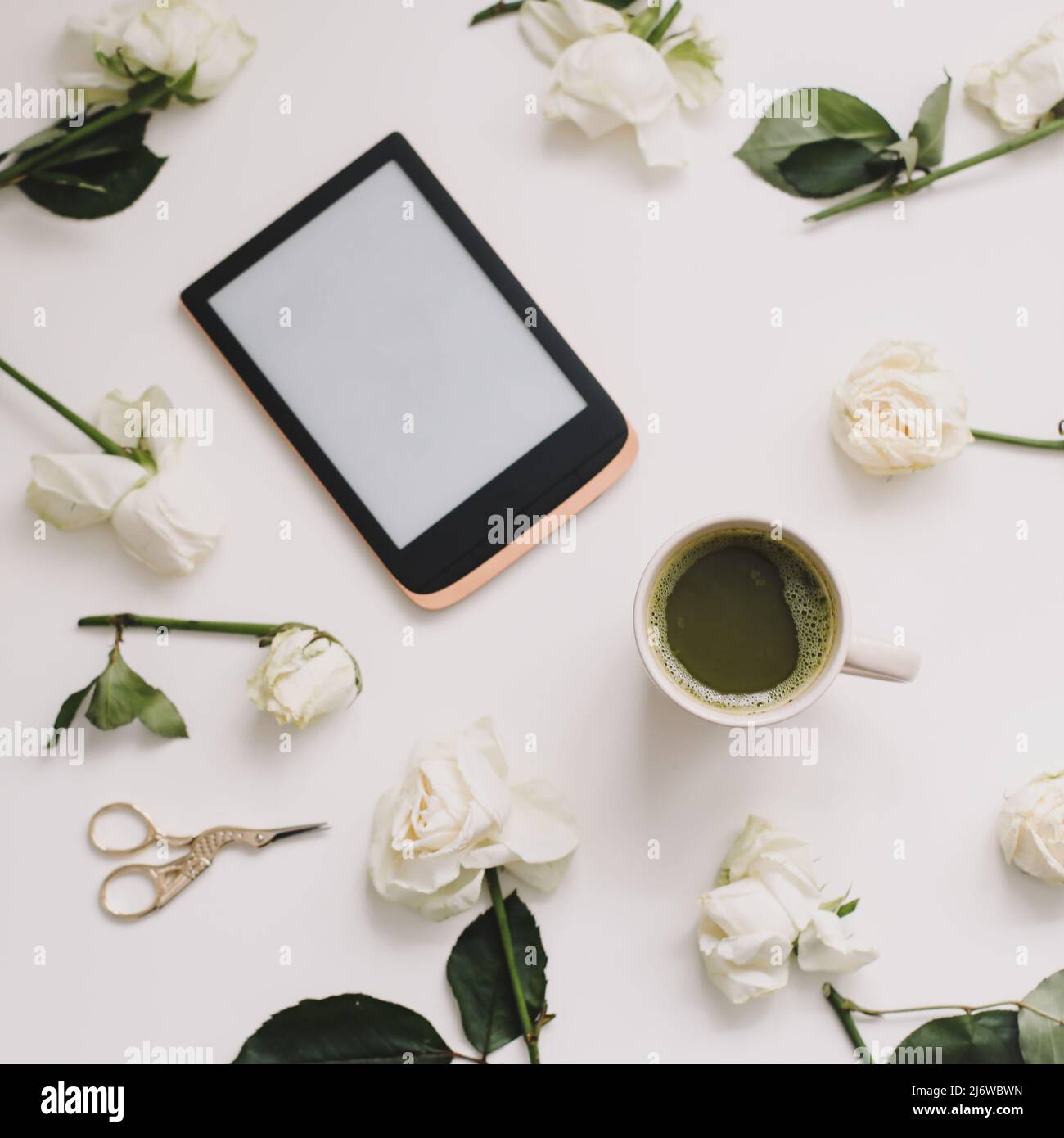 composizione floreale con tavoletta digitale, rose bianche su sfondo bianco. Scrivania da ufficio. Superficie piana, vista dall'alto. Copia modello spazio. Foto Stock