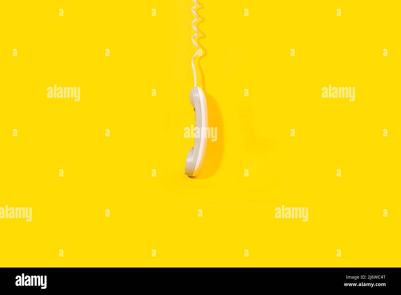 Un ricevitore telefonico digitale sospeso su sfondo giallo con spazio di copia Foto Stock