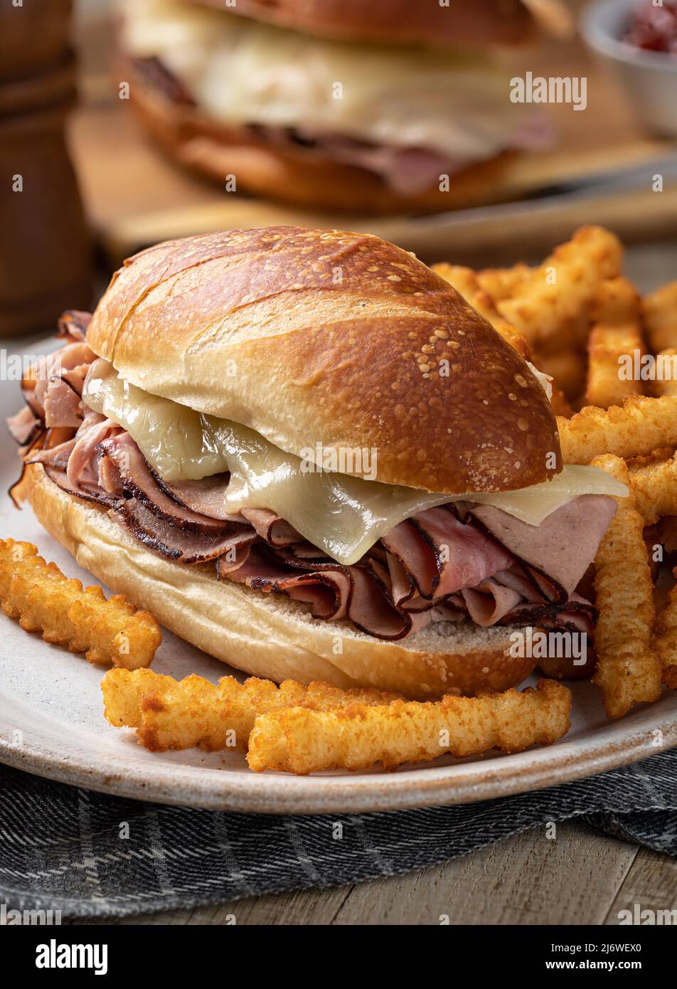 Sandwich sottomarino con prosciutto caldo e formaggio e patatine fritte su un piatto Foto Stock