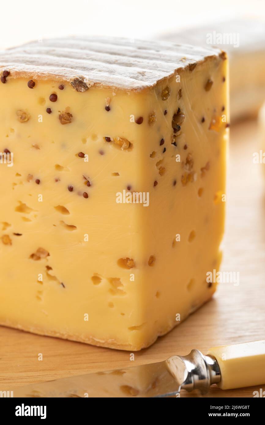 Pezzo di formaggio belga con semi di senape e Fenugreek in primo piano su un tagliere Foto Stock