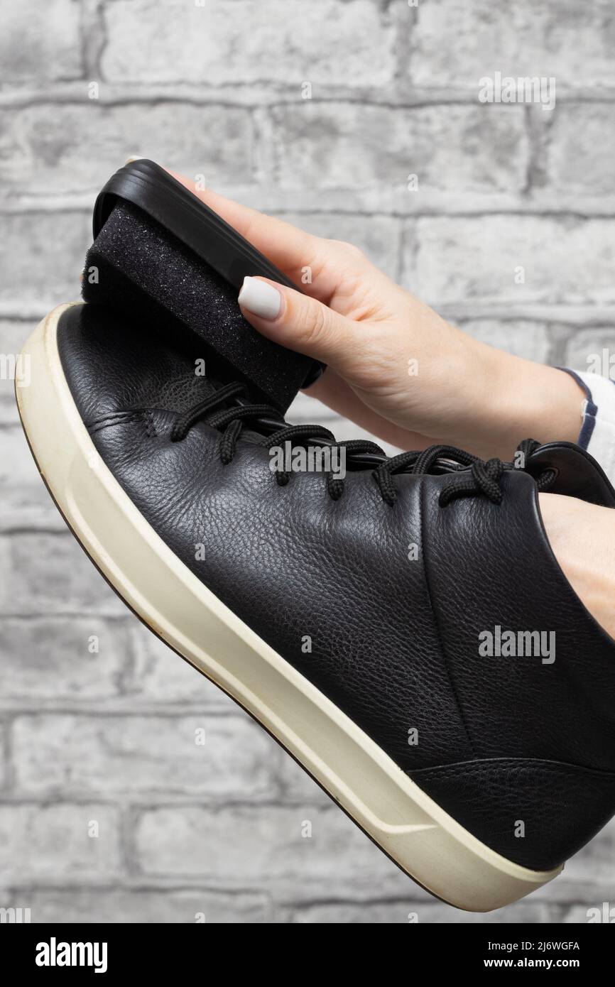 donna strofinando le sue scarpe nere con una spugna Foto Stock
