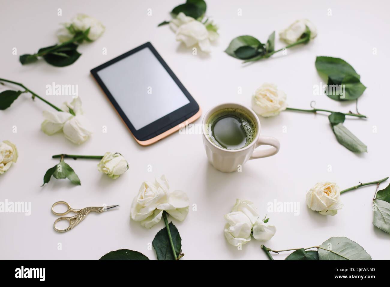 composizione floreale con tavoletta digitale, rose bianche su sfondo bianco. Scrivania da ufficio. Superficie piana, vista dall'alto. Copia modello spazio. Foto Stock