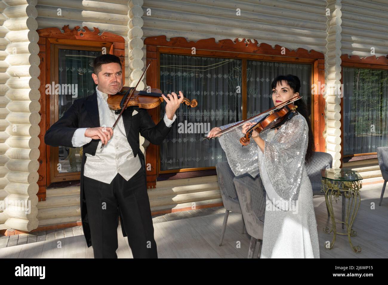 Duo di violinisti. Un uomo in un cappotto di coda e una donna in un abito da sera giocare il violino Foto Stock