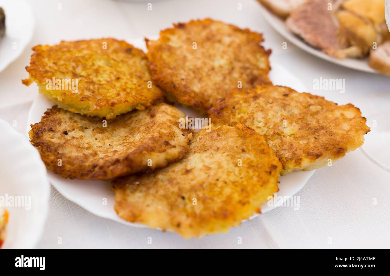 Frittelle di patate grattugiate fritte con panna acida su piatto bianco Foto Stock