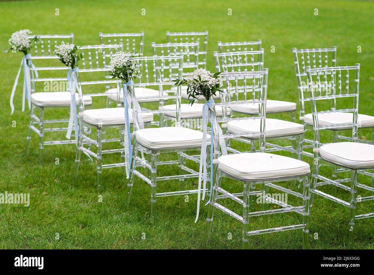 Sedie decorate con fiori per gli ospiti in una cerimonia nuziale all'aperto. Messa a fuoco selettiva soft. Foto Stock