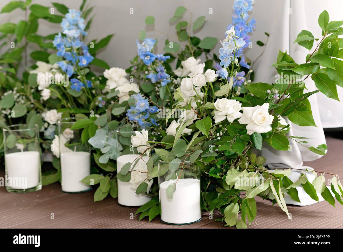 presidio di nozze in ristorante. Tavolo da banchetto per sposi novelli con fiori, verde, candele e luci di ghirlanda. Lussureggiante disposizione floreale. Lusso weddi Foto Stock