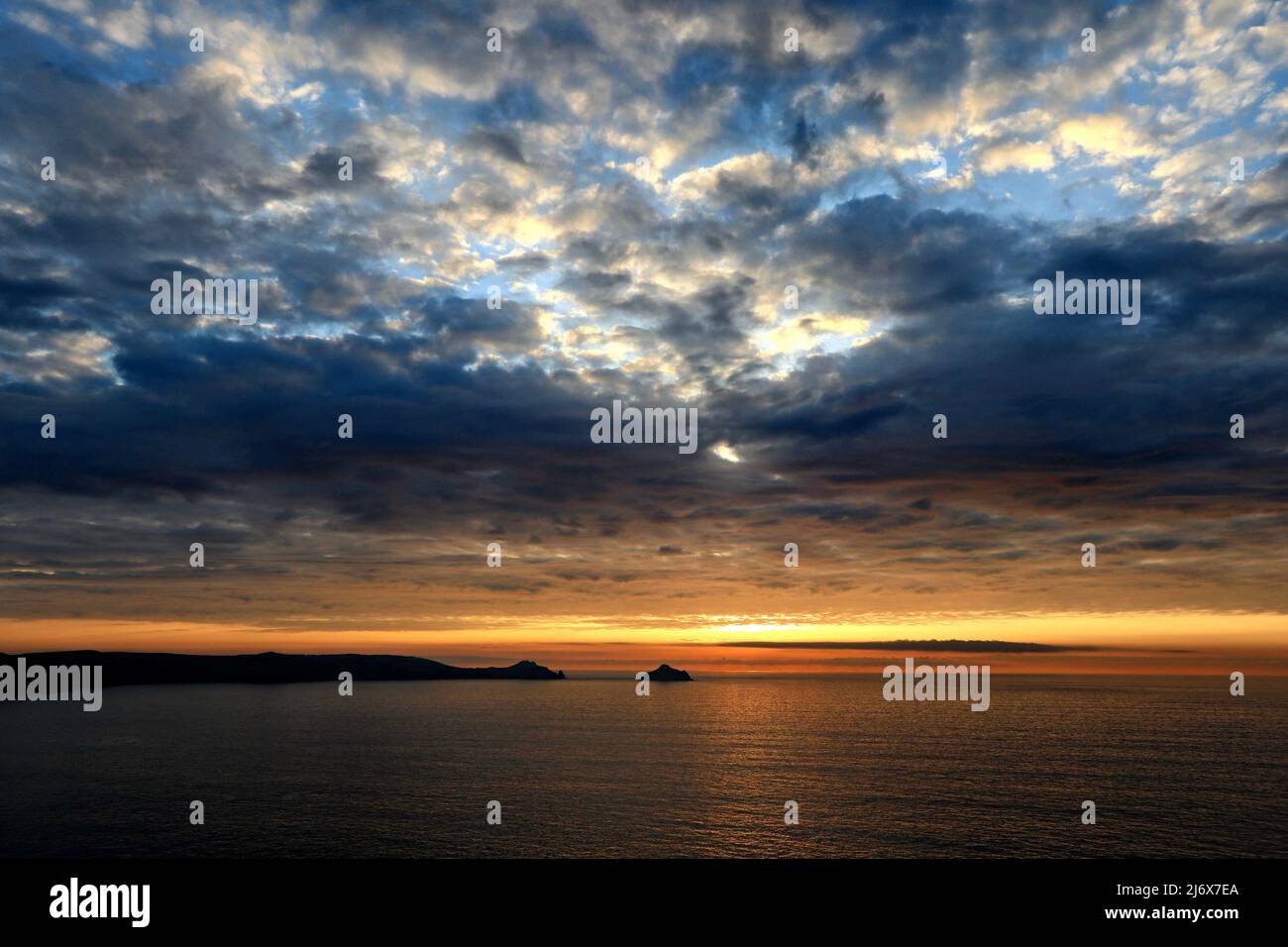 Il sole che tramonta e il cielo serale sulla costa nord della Cornovaglia a Trevan Head vicino a Port Quin. Viste di Pentire Headland, le Rumps e i Mouls. Foto Stock