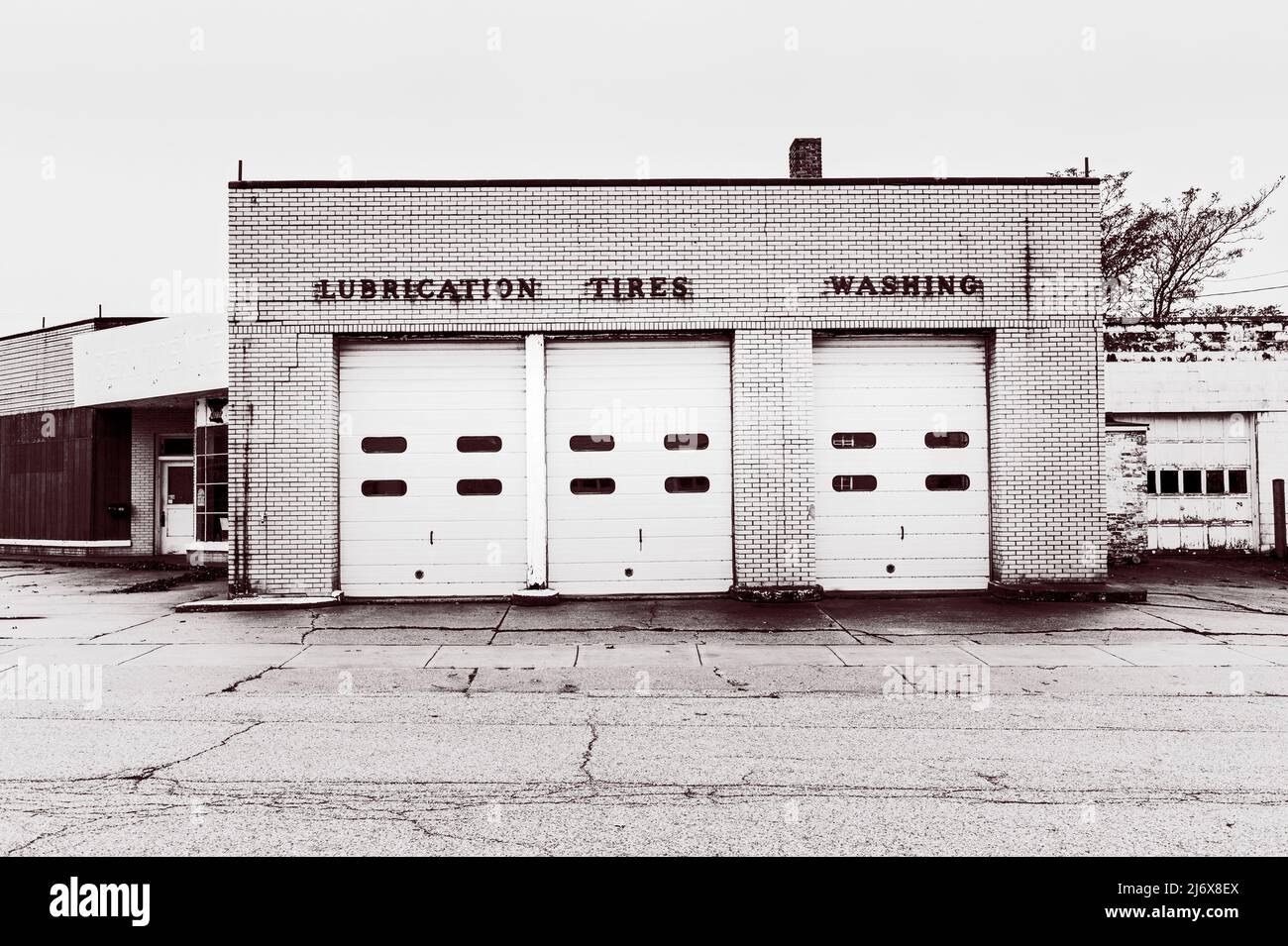 Negozio di riparazione di automobili di design classico, ora demolito, con segnaletica sopra le porte del garage, 'Lubration', 'Tires', 'lavatrice' a Ludington, Michigan. Foto Stock