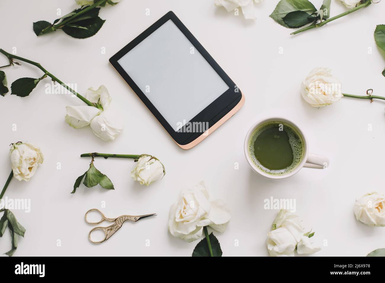 composizione floreale con tavoletta digitale, rose bianche su sfondo bianco. Scrivania da ufficio. Superficie piana, vista dall'alto. Copia modello spazio. Foto Stock