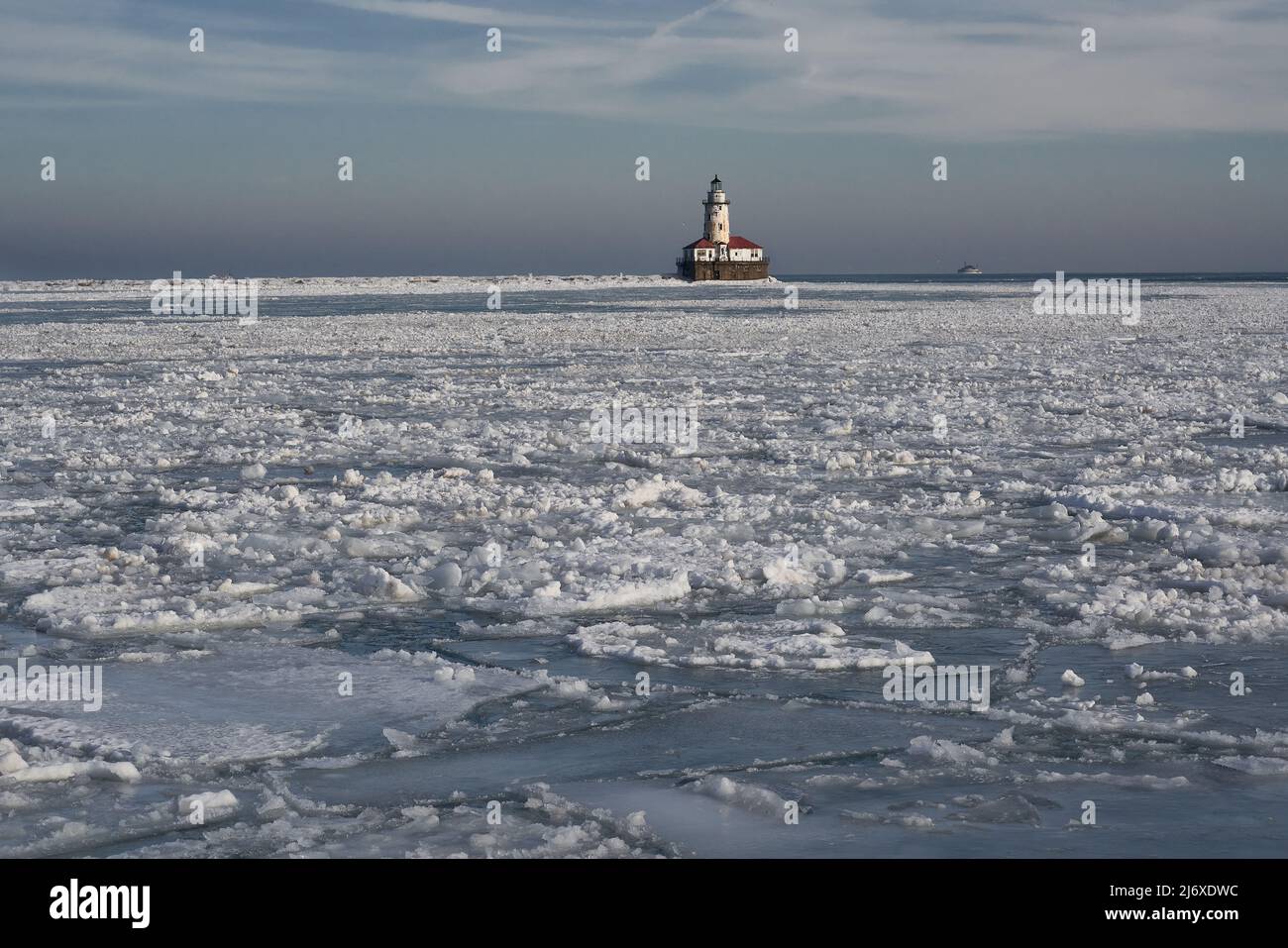 Fredda luce invernale sul lago Michigan con formazioni di ghiaccio di pancake e faro in lontananza Foto Stock