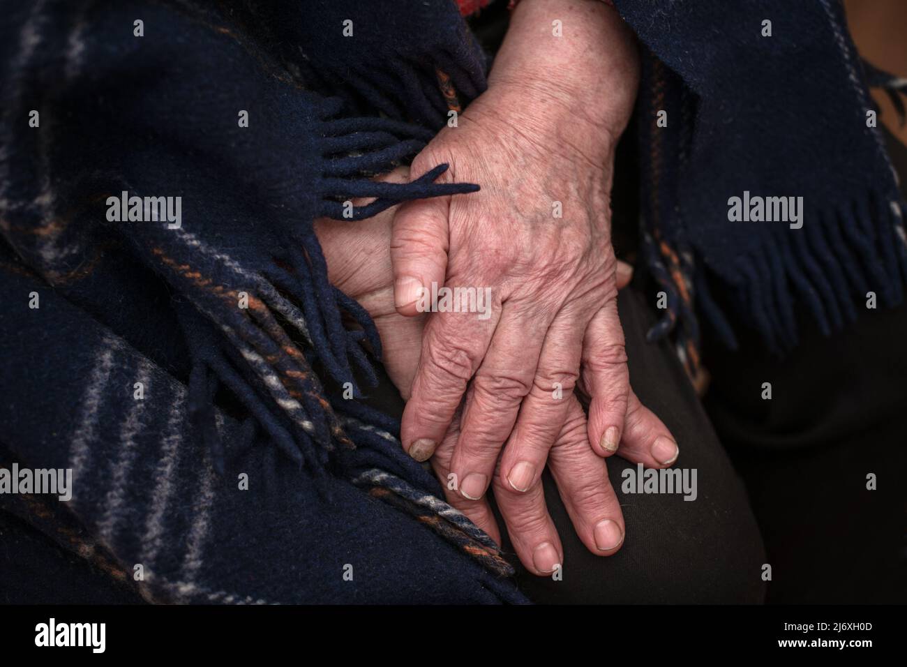 Le mani di una nonna matura di 93 anni con rughe giacciono su una coperta accogliente a casa. Il concetto di amore e cura. Movimento lento. Foto Stock