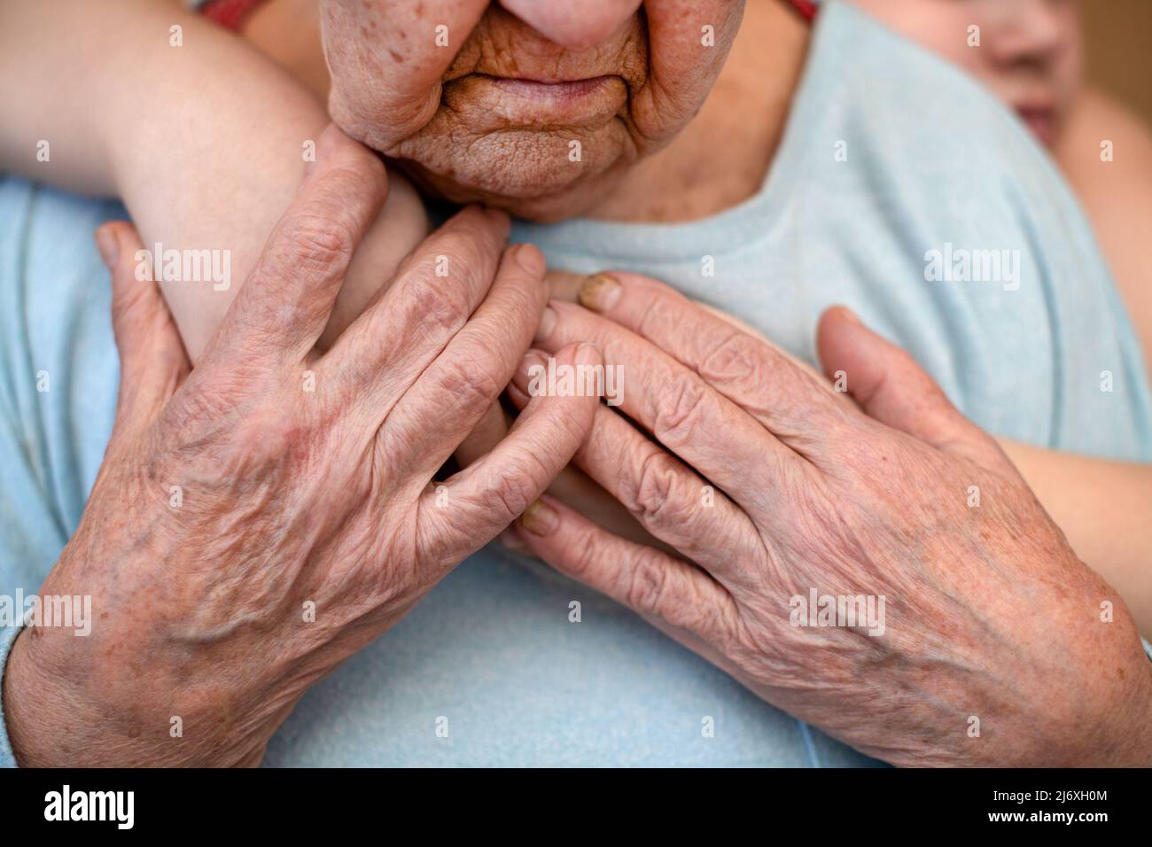 la nonna matura femmina tiene le mani del nipote, che la abbraccia da dietro. Il concetto di amore e cura. Movimento lento Foto Stock
