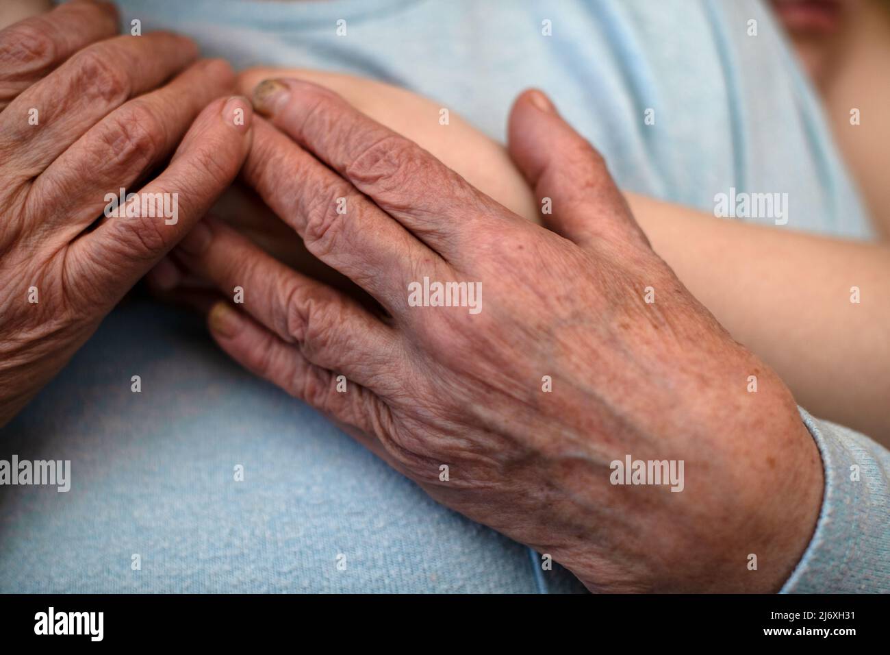 Le mani spiegazzate di una vecchia nonna tengono le mani di un nipote che la abbraccia. Il concetto di amore e cura. Vita lenta. Foto Stock