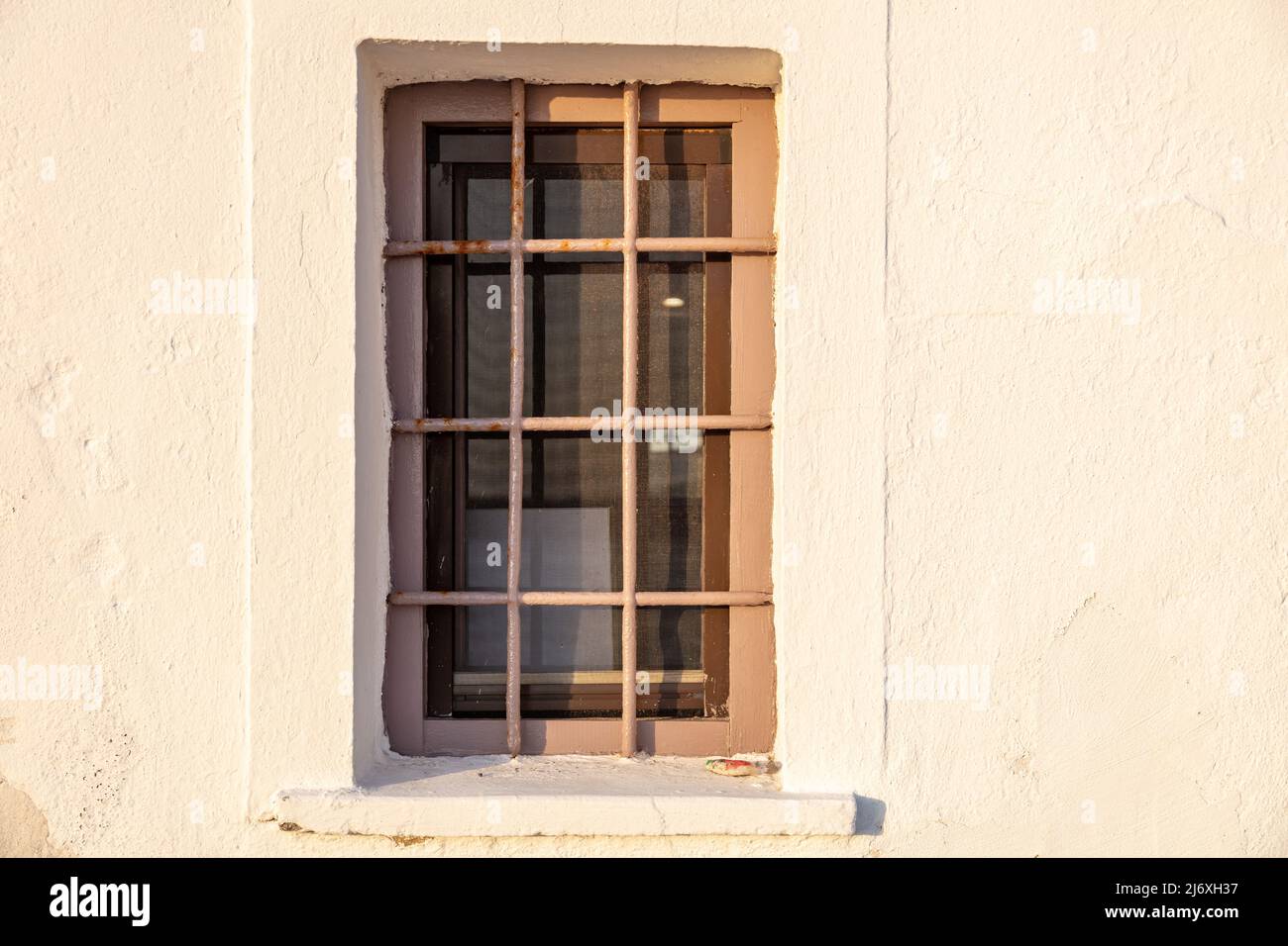 Vecchia finestra e ringhiera in metallo su sfondo bianco. Sicurezza della casa, vista frontale. Architettura tradizionale in Grecia Foto Stock