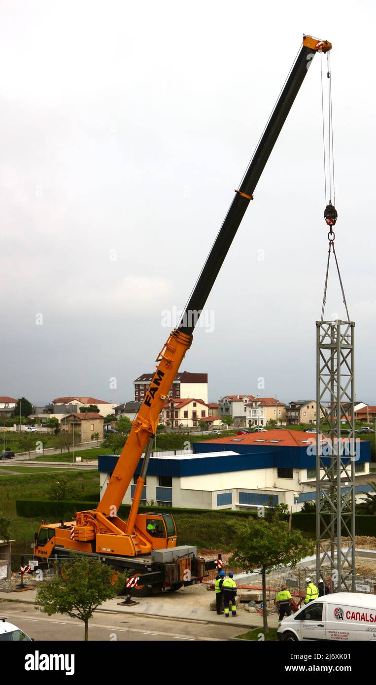 Prima sezione dell'albero di una gru a torre che viene sollevata in posizione da una gru montata su autocarro in un cantiere Santander Cantabria Spagna Foto Stock