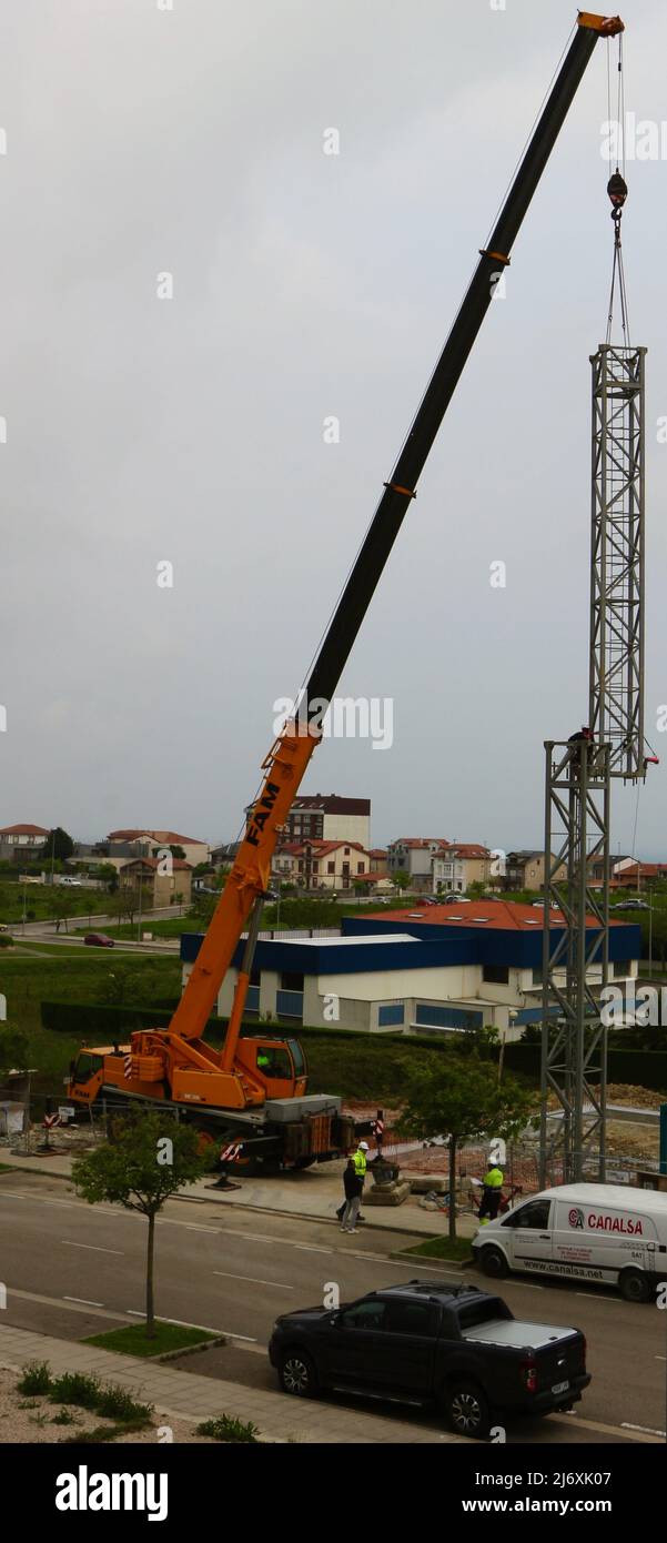 La seconda sezione dell'albero di una gru a torre è stata sollevata in posizione da una gru montata su autocarro in un cantiere Santander Cantabria Spagna Foto Stock