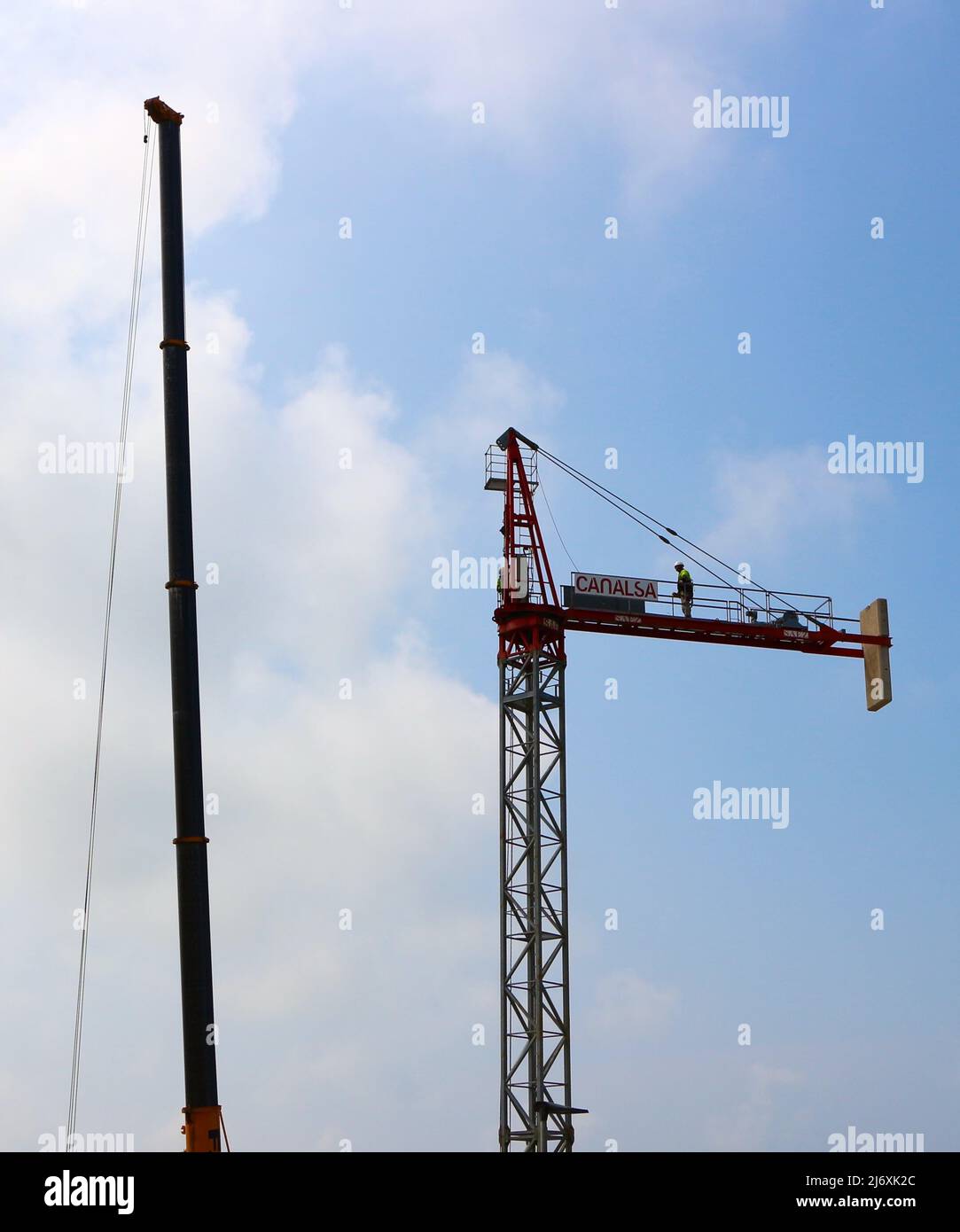 Il braccio di una gru mobile accanto ad una gru a torre parzialmente assemblata durante il suo assemblaggio Santander Cantabria Spagna Foto Stock