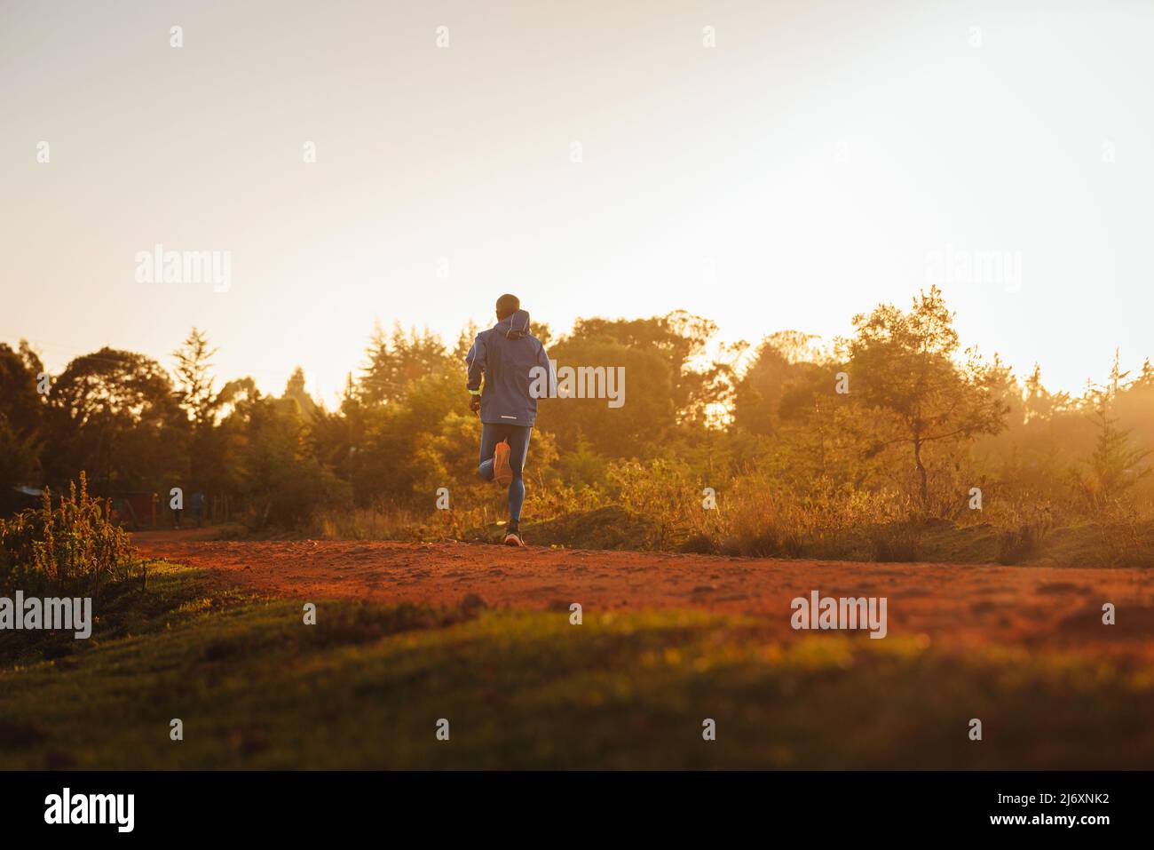 Maratoner keniano durante l'addestramento in Africa. Città di Iten, Kenya. Formazione maratona su strade di terra rossa in Africa. Vicino alla città di Eldored. Grande Rift Foto Stock