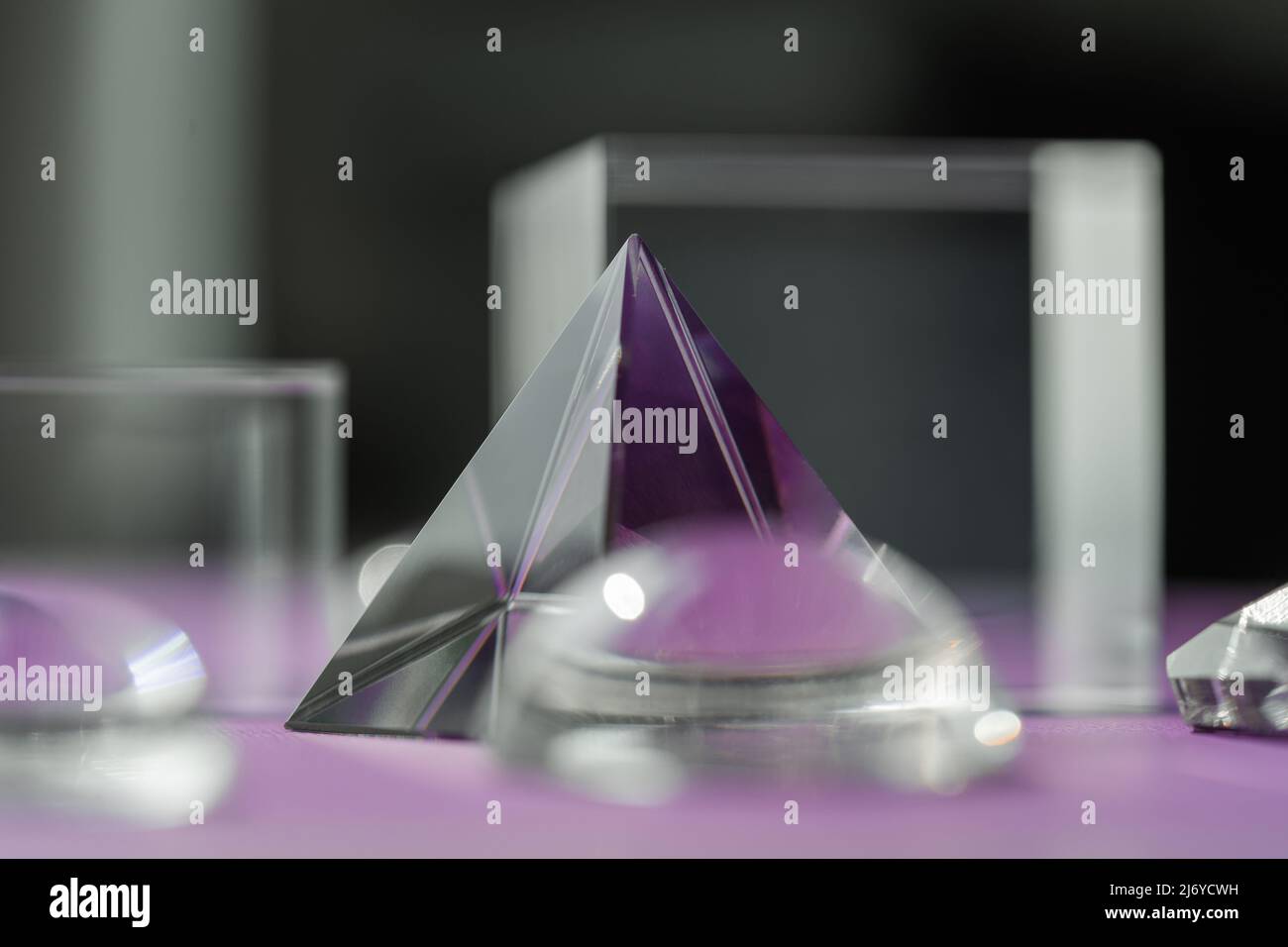 Luce rifrangente a prisma di cristallo, cristalli magici e piramide, sfera e cubo su sfondo viola. Pratica di cristallo di guarigione spirituale. Feng Shui, bravo Foto Stock