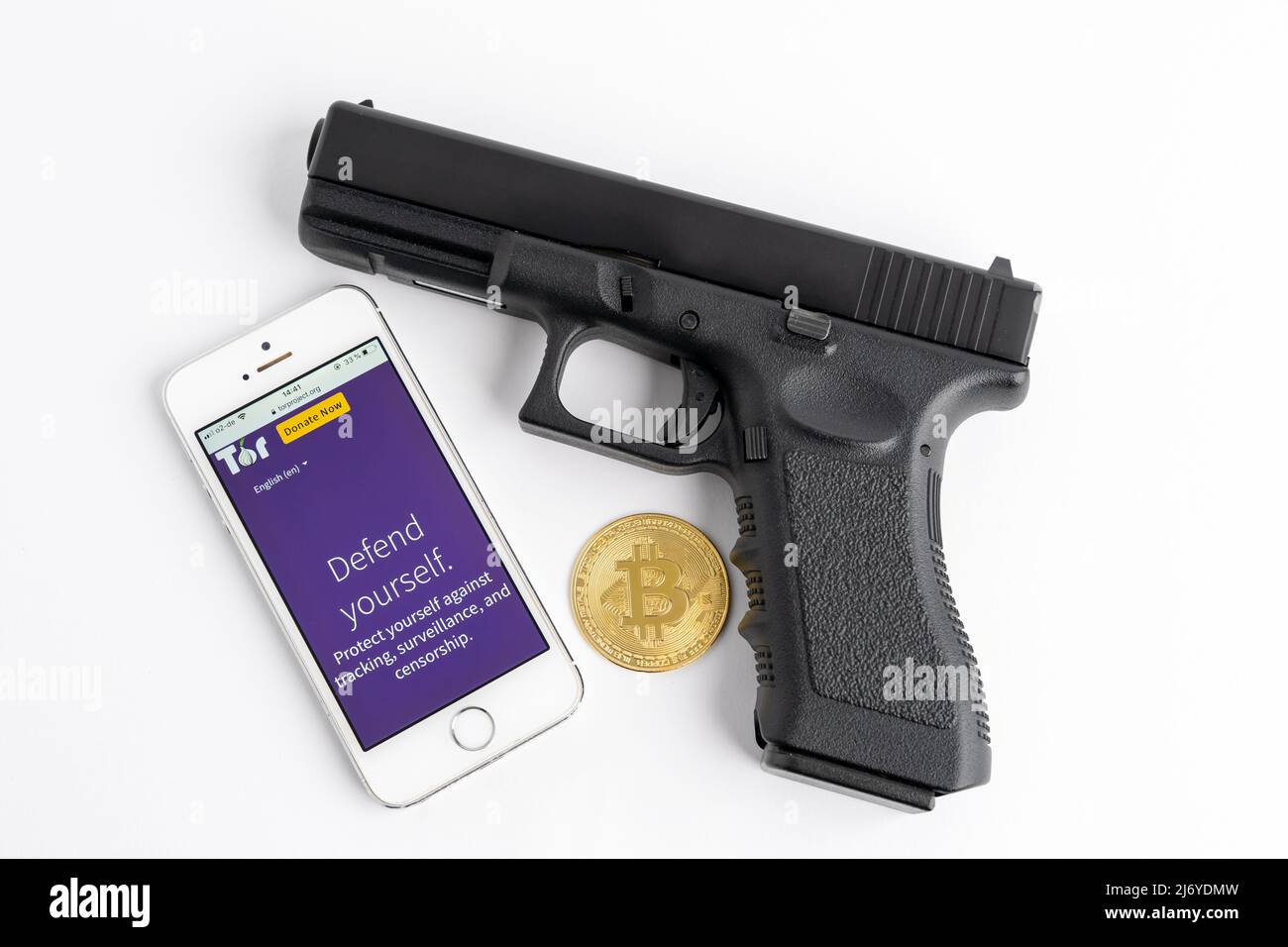 Tor browser su uno smartphone, una pistola e un Bitcoin come simboli per il darknet. Usando i soldi del BTC nel fotoricettore scuro per comprare le cose illegali come un'arma. Foto Stock