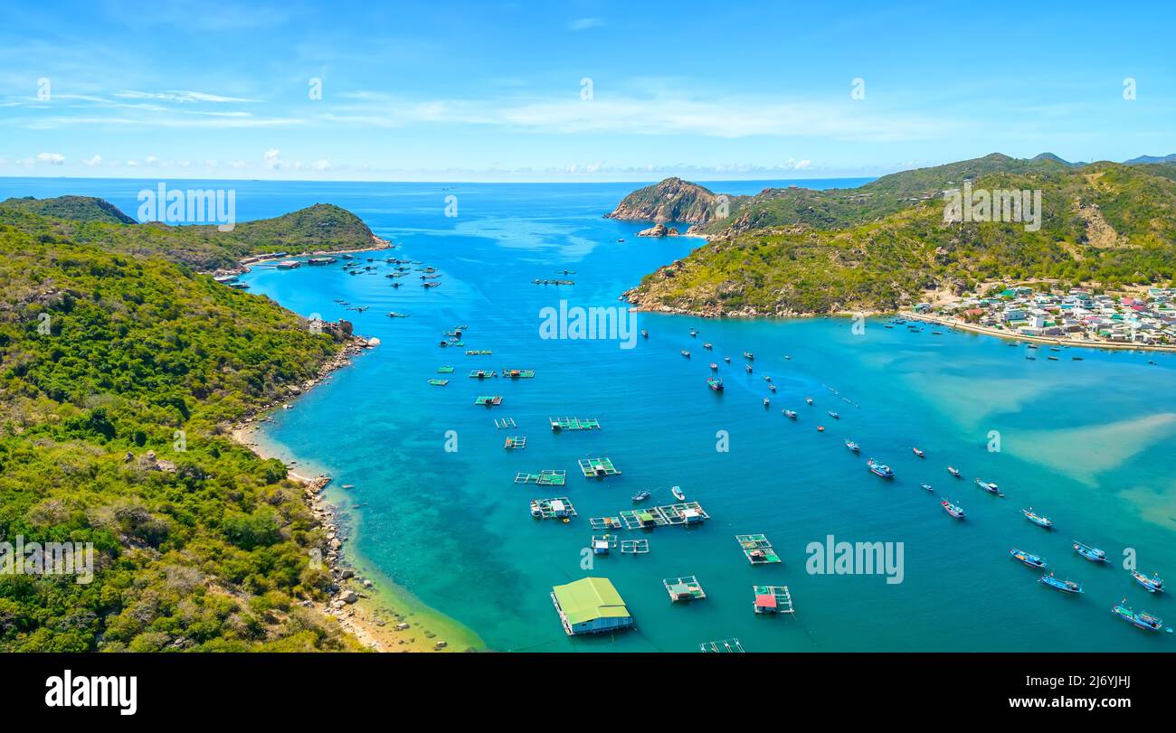 Vinh Hy Bay visto dall'alto a mezzogiorno d'estate con centinaia di barche da pesca ormeggiate e villaggi di pescatori sotto. Foto Stock