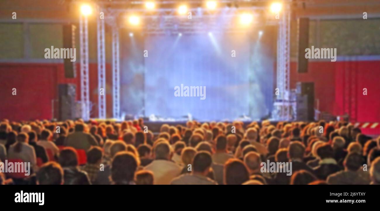 intenzionalmente offuscato ideale come sfondo con persone spettatori in attesa per l'inizio del concerto in teatro con il palco senza alcuno e cu Foto Stock