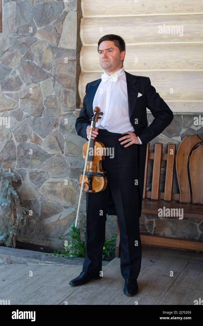 Vicino all'edificio si trova un violinista con violino. Foto Stock