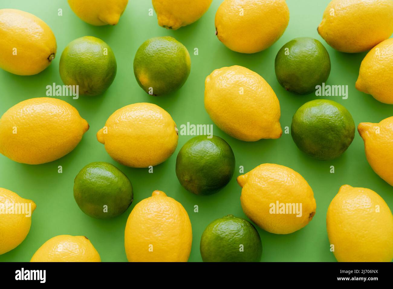 Posa piatta di limoni e lime su sfondo verde Foto Stock