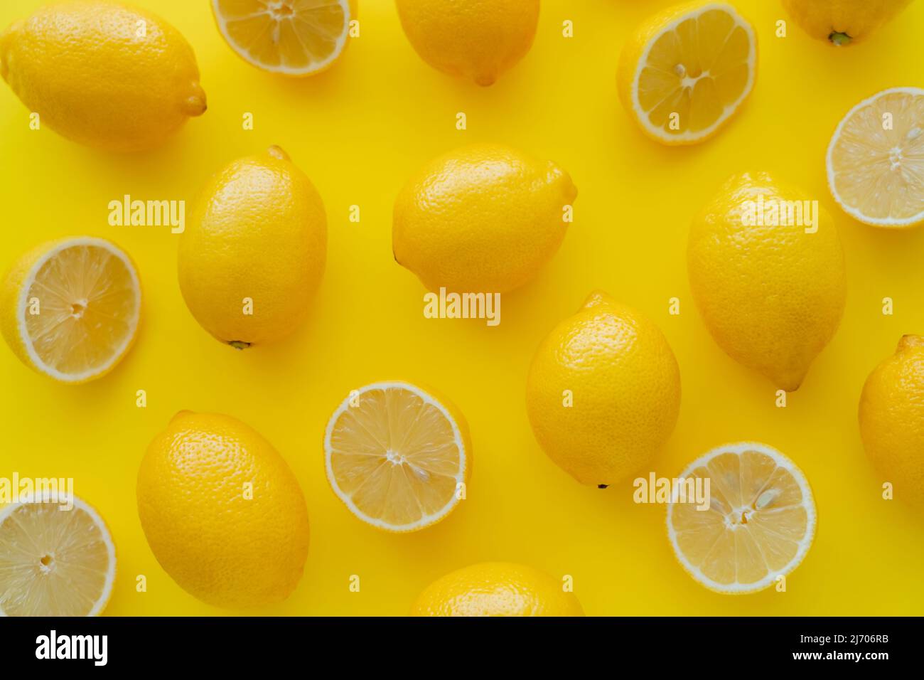Posa piatta di limoni luminosi sulla superficie gialla Foto Stock