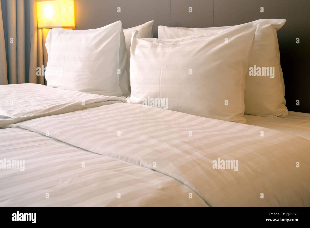 Interno di una camera in Hotel con cuscini bianchi e biancheria da letto Foto Stock